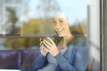 Wall Mural - Woman drinking coffee loooking outside on a couch