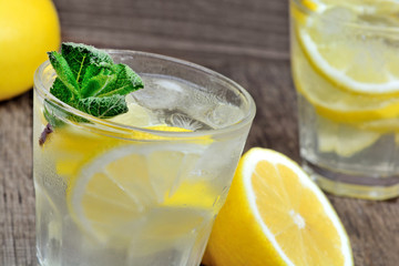 Wall Mural - Water with fresh lemon and mint in a glasses on wood table