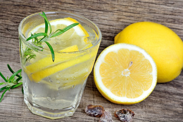 Wall Mural - Tasty cool beverage with lemon and rosemary on wood table