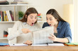 Two amazed students reading a newspaper