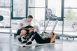 © LIGHTFIELD STUDIOS - male personal trainer with timer and athletic woman doing abs on fitness mat at gym