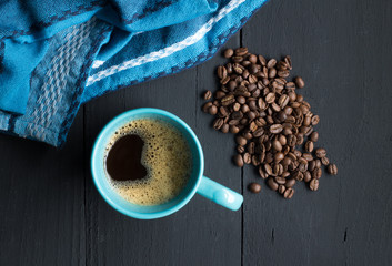 Coffee mug on rustic black wooden kitchen table with coffee beans and space for text