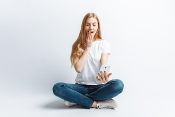 Beautiful young girl talking on the phone, surprise and shock at the girl from news or discounts, in the Studio, isolated background, cheerful and positive