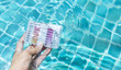 © sirirak - Swimming pool check kit in girl hand dipping in clear water, summer outdoor day light, water quality test kit