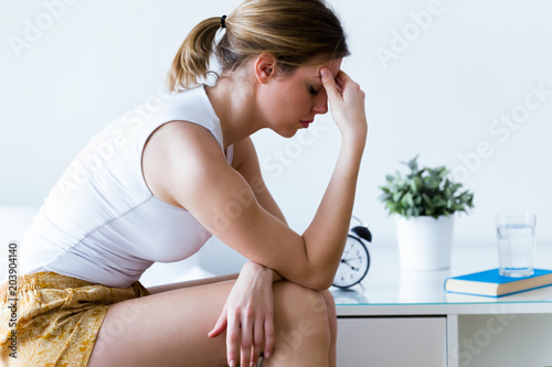 Fotografia Unhappy lonely depressed young woman sitting on bed at home