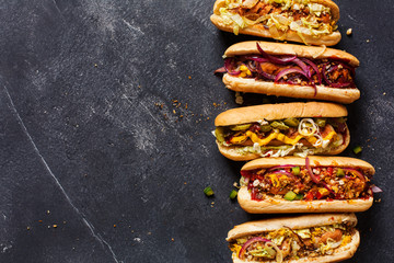 Hot dogs with different toppings on a dark background.