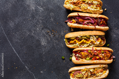 Fotografía Hot dogs with different toppings on a dark background.