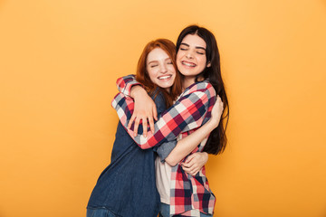 Wall Mural - Portrait of two delighted young teenage girls hugging