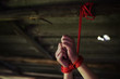 Closeup hostage hands tied by red rope