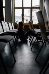 young pretty woman sitting in co-working office, conference room. Woman waiting for conference. Empty office room. One busines lady.