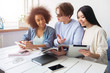 © estradaanton - Three smart students are sitting together and studying. Guy wears glasses and looking to the girl's phone while the girls in are looking to the journal that guy has.
