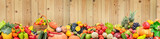 Panoramic photo healthy vegetables and fruits against light wooden wall.
