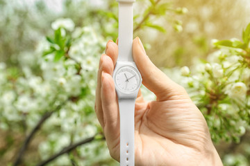 Poster - Woman holding beautiful wristwatch on blurred background, focus on hand. Time change concept
