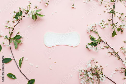 Fotografia The sanitary napkin lying with blossom on pink background.