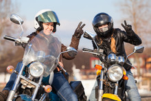 Victory Signs In Leather Gloves From Two Laughing Female Bikers With Street Motorcycles