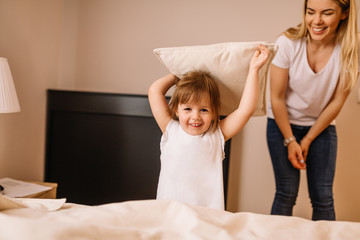 Wall Mural - Happy child with parents having pillow fight in bed at home