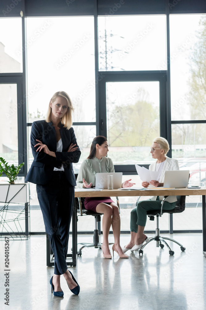 beautiful businesswoman standing with crossed arms at meeting in office - obrazy, fototapety, plakaty 