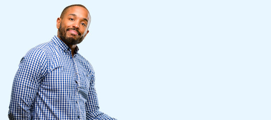 Wall Mural - African american man with beard confident and happy with a big natural smile inviting to enter isolated over blue background