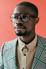 Wall Mural - portrait of stylish african american man in trendy eyeglasses, isolated on red