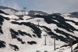 Widok trasy narciarskiej i wyciągu w górach po sezonie zimowym, resztki śniegu opnieją, widać ziemię, roślinność, pusto