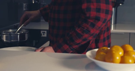 young man poaching eggs at home