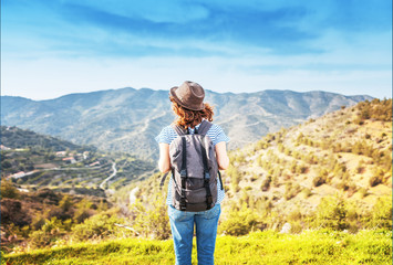 Wanderlust and travel concept. stylish traveler woman in hat looking at mountains. hipster girl traveling on top of mountain, looking in front. space for text. atmospheric moment