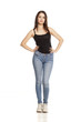 young woman in jeans and shirt stands on a white background