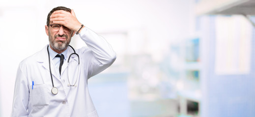 Poster - Doctor senior man, medical professional terrified and nervous expressing anxiety and panic gesture, overwhelmed at hospital