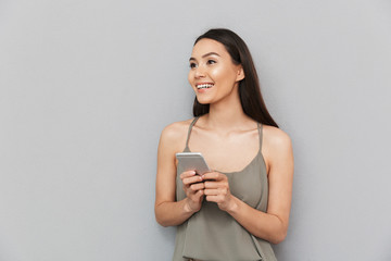 Wall Mural - Portrait of a smiling asian woman holding mobile phone