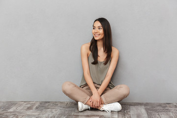 Sticker - Portrait of a smiling asian woman sitting on a floor