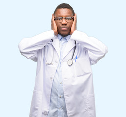 Wall Mural - Young black doctor, medical professional covering ears ignoring annoying loud noise, plugs ears to avoid hearing sound. Noisy music is a problem.