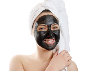  close-up portrait beautiful woman with facial black mask on white background, girl with a white towel on her head, satisfied and happy  smile