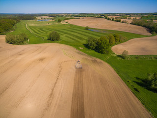 Wall Mural - aerial view - a modern tractor working on the agricultural field - tractor plowing and sowing in the agricultural field - high top view