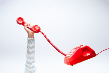 Hand holding up red telephone