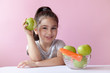 © kaganskaya115 - A cute little girl eating fresh vegetables. A portrait on а pastel background. Healthy teeth.