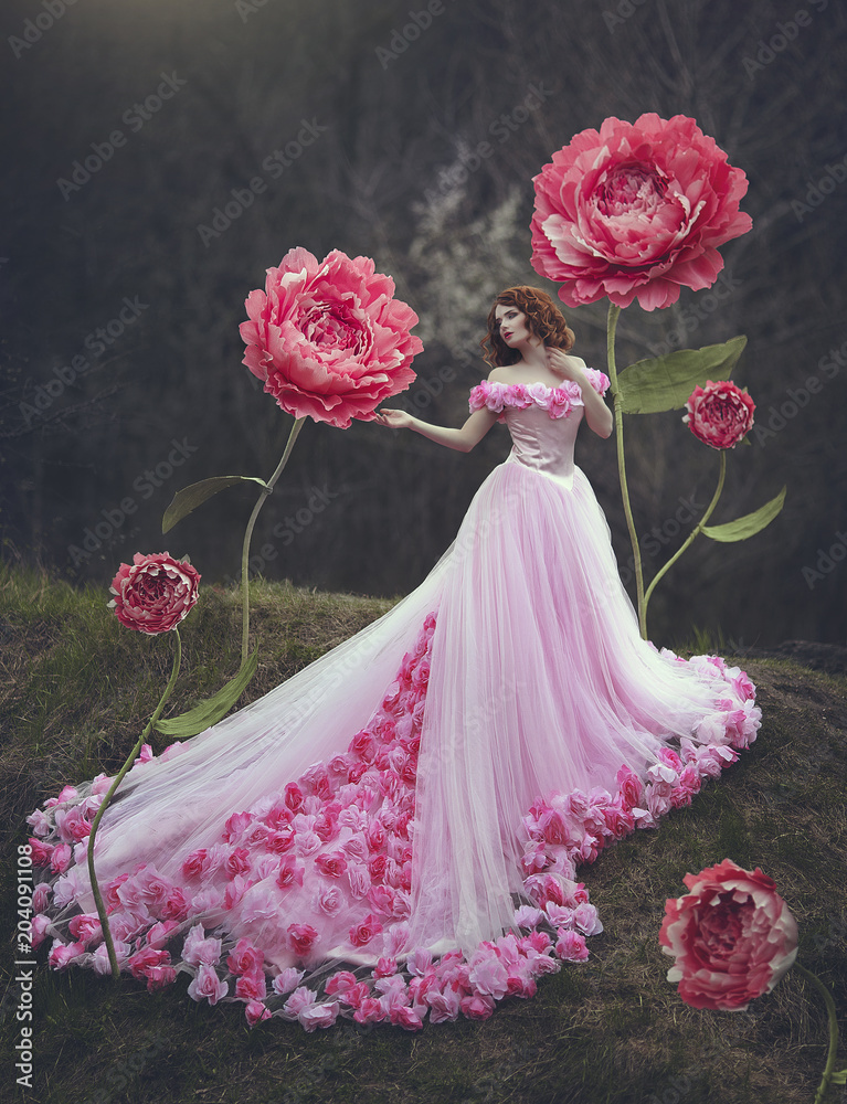 Photo Stock Beautiful sensual girl with red hair in a fairy pink dress with  a huge train posing near the giant flowers of a pink peony. The girl is a  flower princess. |