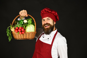 Handsome chef holding a basket of fresh vegetables