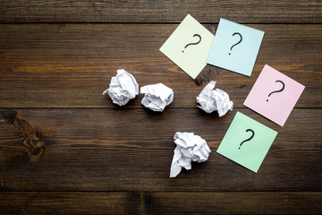 Poster - FAQ concept. Question mark on sticky notes near crumpled paper on dark wooden background top view copy space