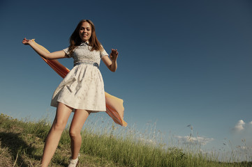 Wall Mural - BEAUTIFUL BLONDE GIRL LAUGHS AND DANCES OUTDOORS WITH AN ORANGE SCARF IN HER HANDS