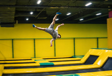 Trampoline Jumper Performs Complex Acrobatic Exercises And Somersault On The Trampoline.