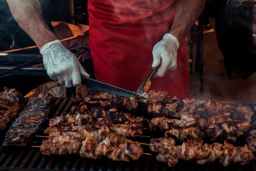 the man is preparing a meat barbecue on the grill