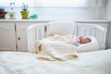 Wall Mural - Newborn baby having a nap in co-sleeper crib attached to parents' bed