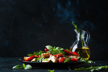 Salad with arugula, strawberries and chicken, dark background, selective focus