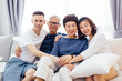 © twinsterphoto - Asian family with adult children and senior parents relaxing on a sofa at home together