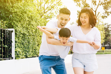 Asian family having fun and carrying a child in public park