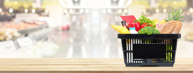 Shopping basket full of food and groceries on the table in supermarket