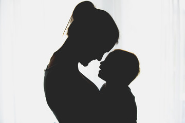 Canvas Print - Young mother, embracing with tenderness and care her baby boy, smiling happily