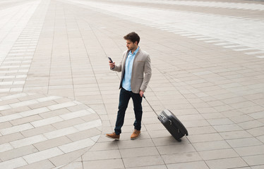 Professionalism is inside! Young businessman walking at outdoors with luggage in the routine of working with determination and confidence.