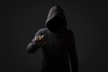 Faceless Man In A Hood With Points A Finger At The Viewer On A Dark Background. Concept Threats And Terror