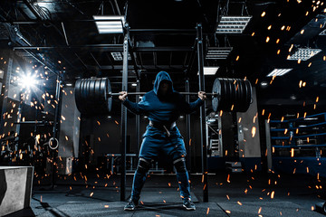 Wall Mural -  A man in the gym is holding a heavy barbell on his shoulders